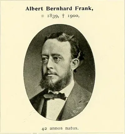 Reprodukcja drukowanej tablicy portretowej: u góry nazwisko Albert Bernhard Frank oraz daty 1839 i 1900, pośrodku owalny portret fotograficzny brodatego mężczyzny w ciemnym surducie, kamizelce i muszce, u dołu podpis „42 annos natus”.
